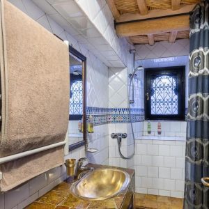 Ванная комната с раковиной, зеркалом и отделкой в марокканском стиле.