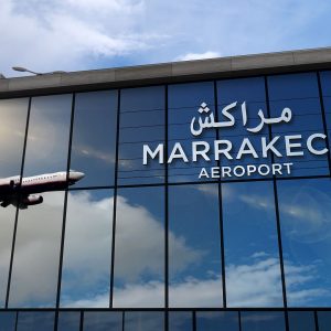 Здание аэропорта Марракеша с отражением самолета на стеклянной фасаде.